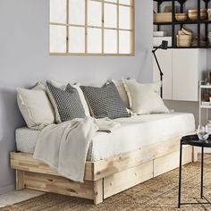 a bed with pillows and blankets on it in a room next to a wall mounted bookshelf