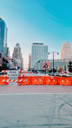 an orange barricade sitting on the side of a road next to tall buildings