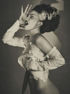 an old photo of a woman holding a knife in her hand and making the v sign