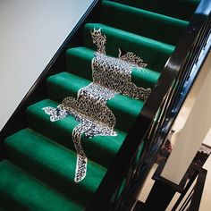 the stairs are decorated with animal designs on green carpeted stair treads and black handrails