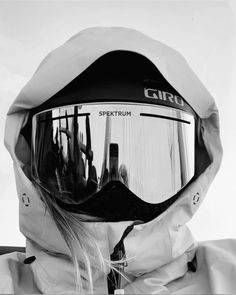 black and white photograph of a person wearing ski goggles with the reflection of their skis on them