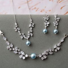 Bridal jewellery set  Set of 3 Colour: rhodium(silver tone) /clear/blue NOTE:Some details can be little bit different!   Measurements: -earrings  approx 3.8 cm(   not large ), faux parl 8 mm -necklace approx 18 inches(+1.5 inches), crystal part approx 7.8 cm (approx 3 inches), faux pearl 10 mm -bracelet approx 16.8 cm, width 12 mm, faux pearl 10mm Materials:  rhodium over brass components, zircon crystals, lt.blue Swarovski faux pearls. Stud earrings. Great for wedding or other celebration. MORE JEWELRY: https://www.etsy.com/uk/shop/BridalArtDeco?ref=seller-platform-mcnav&search_query=jewelry MATCHING HAIR ACCESSORIES: https://www.etsy.com/uk/shop/BridalArtDeco?ref=seller-platform-mcnav&search_query=hair Please note some images have been enlarged to allow for details to be shown. Read the Light Blue Jewelry Set, Blue Bridal Jewelry, Pearl Drop Earrings Wedding, Bridal Jewelry Pearl Sets, Jewelry Matching, Drop Earrings Wedding, Wedding Earrings Drop, Bridal Jewelry Set, Large Necklace