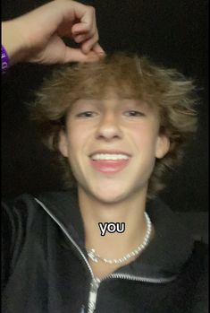 a young man with blonde hair smiling and holding his hand on top of his head