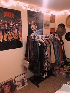 a room filled with clothes and posters on the wall