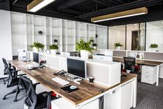 an empty office with desks and computers on the tables in front of them are potted plants