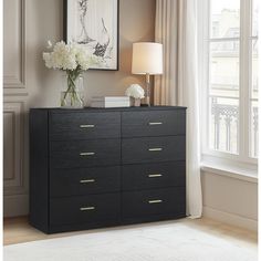 a black dresser with white flowers and a painting on the wall behind it in a living room