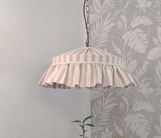 a pink and white striped umbrella hanging from a metal hook next to a potted plant