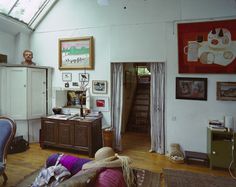 a living room filled with furniture and pictures on the wall next to a dresser in front of a window