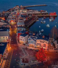 an aerial view of a town at night with boats in the water and lights on