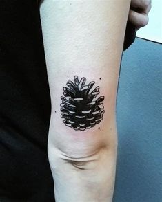 a small pine cone tattoo on the arm