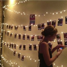 a woman looking at her cell phone in front of a wall with pictures on it