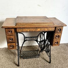 an old sewing machine sitting on top of a wooden table next to a white wall