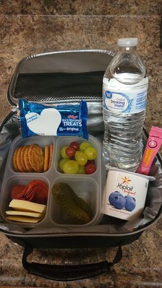 an open lunch box with water, crackers and fruit