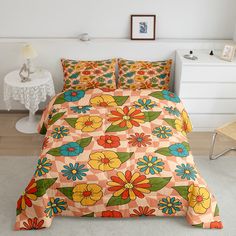 a bed with colorful flowers on it in a room next to a white table and chair