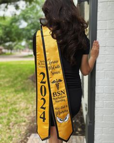 a woman wearing a yellow sash with the words bsn on it, standing in front of a door