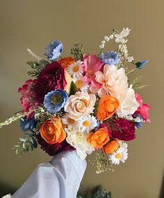 a bouquet of colorful flowers in someone's hand