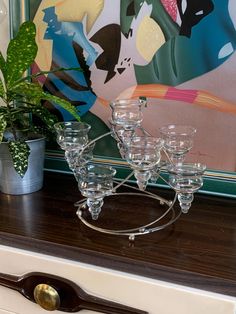 a set of glasses on top of a dresser next to a potted plant