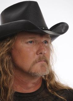 a man with long hair wearing a black cowboy hat and looking off to the side