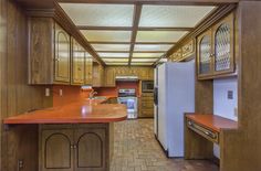 a kitchen with wooden cabinets and white refrigerator freezer next to an island in the middle