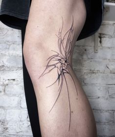 a woman's leg with a tattoo on it that looks like a tree branch