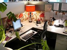 an office cubicle with a computer, keyboard and lamp on it's desk