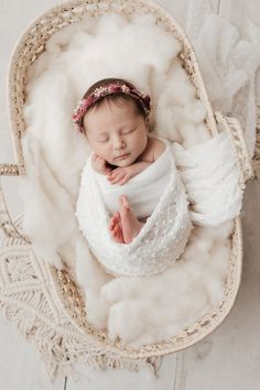 a baby is sleeping in a basket with fluffy white blankets on it's sides