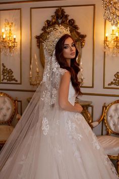 a woman in a wedding dress standing next to a gold and white wall with chandelier