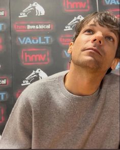 a man is sitting in front of a wall with red and blue signs on it