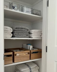 an organized closet with folded towels and linens in bins on the bottom shelf