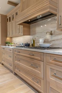 a large kitchen with wooden cabinets and marble counter tops, along with hardwood flooring