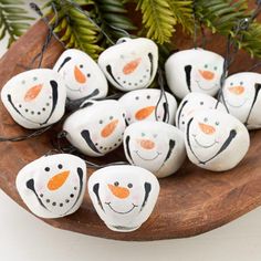 some white and orange painted rocks on a wooden plate with pine branches in the background