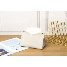 a white bag sitting on top of a wooden floor next to a magazine rack and napkin holder