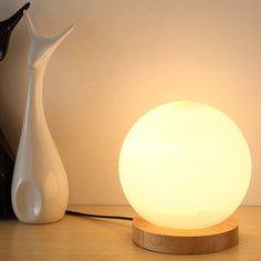 a white lamp sitting on top of a wooden table next to a black cat figurine