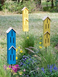 three birdhouses in the middle of a flower garden