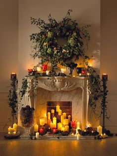 a fireplace with candles and greenery around it