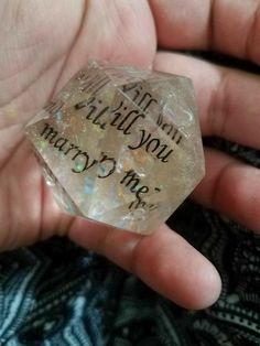 someone is holding a small crystal stone with writing on it