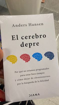 a person holding up a book with three different colored brain images on it's cover