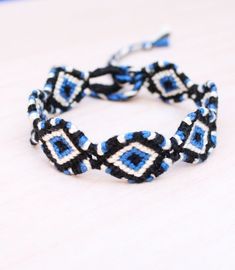 a close up of a bracelet on a wooden table with blue and white squares in the middle