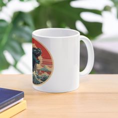 a white coffee mug sitting on top of a wooden table next to a book and plant