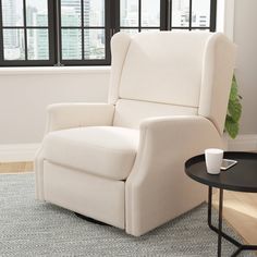 a white recliner chair sitting on top of a rug in a living room next to a window