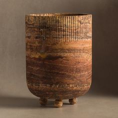 a wooden vase sitting on top of a table next to a brown wall and floor