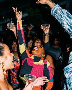 a group of people standing next to each other at a party with their hands in the air