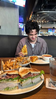 a man sitting at a table with a large sandwich and fries in front of him