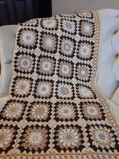 a brown and white crocheted blanket sitting on top of a couch