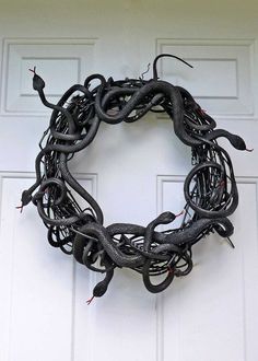 a wreath made out of wires on the side of a white door with a black snake hanging from it's center