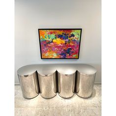 an abstract painting hangs on the wall above three stools in front of a marble floor