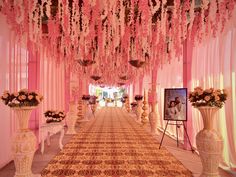 an aisle decorated with pink flowers and white vases on either side of the aisle