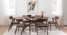 a dining table with four chairs and a vase on the table in front of it