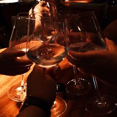 several people are holding wine glasses at a table with their hands on top of them