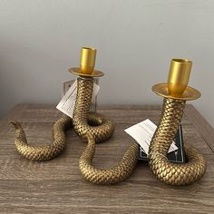 two gold candlesticks sitting next to each other on top of a wooden table